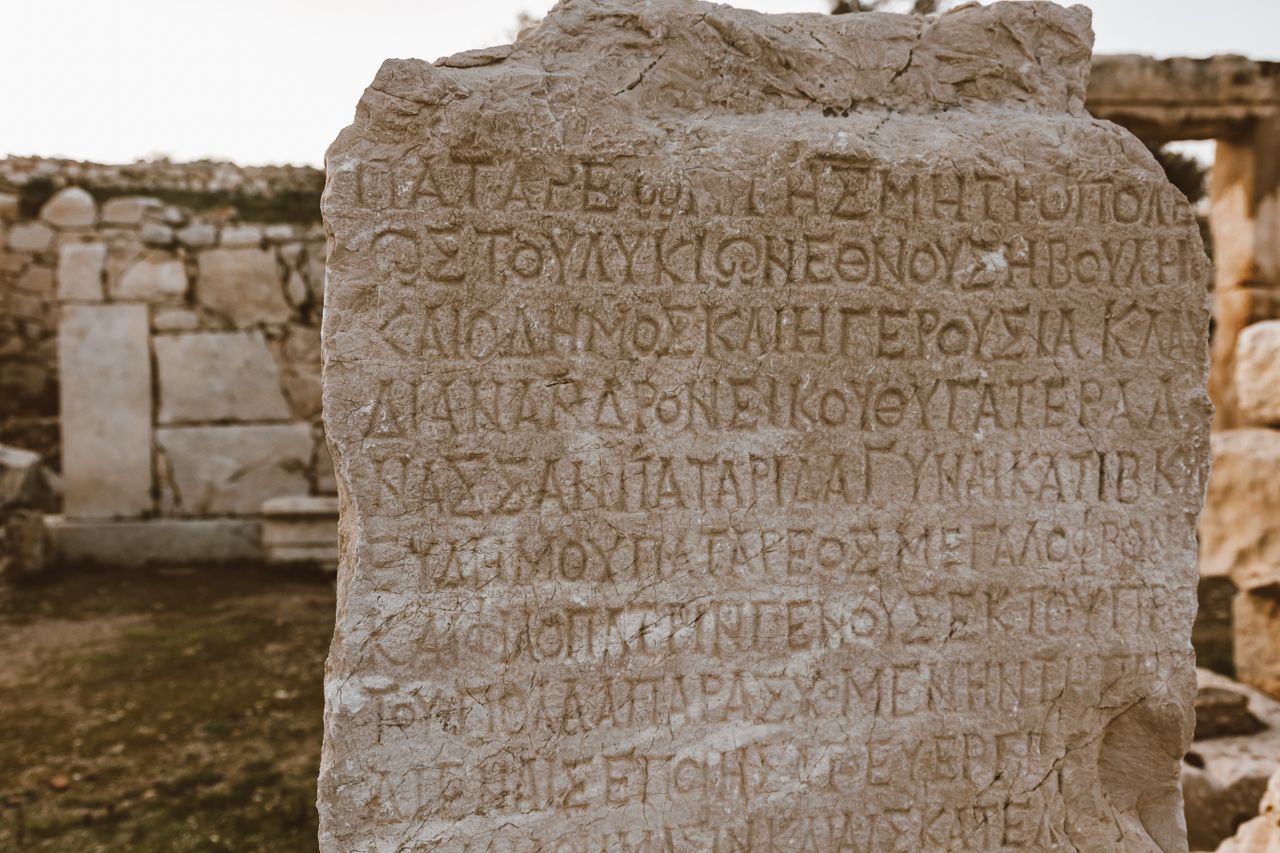 services-05 Close-up of an ancient Greek inscribed stone in an archaeological site.